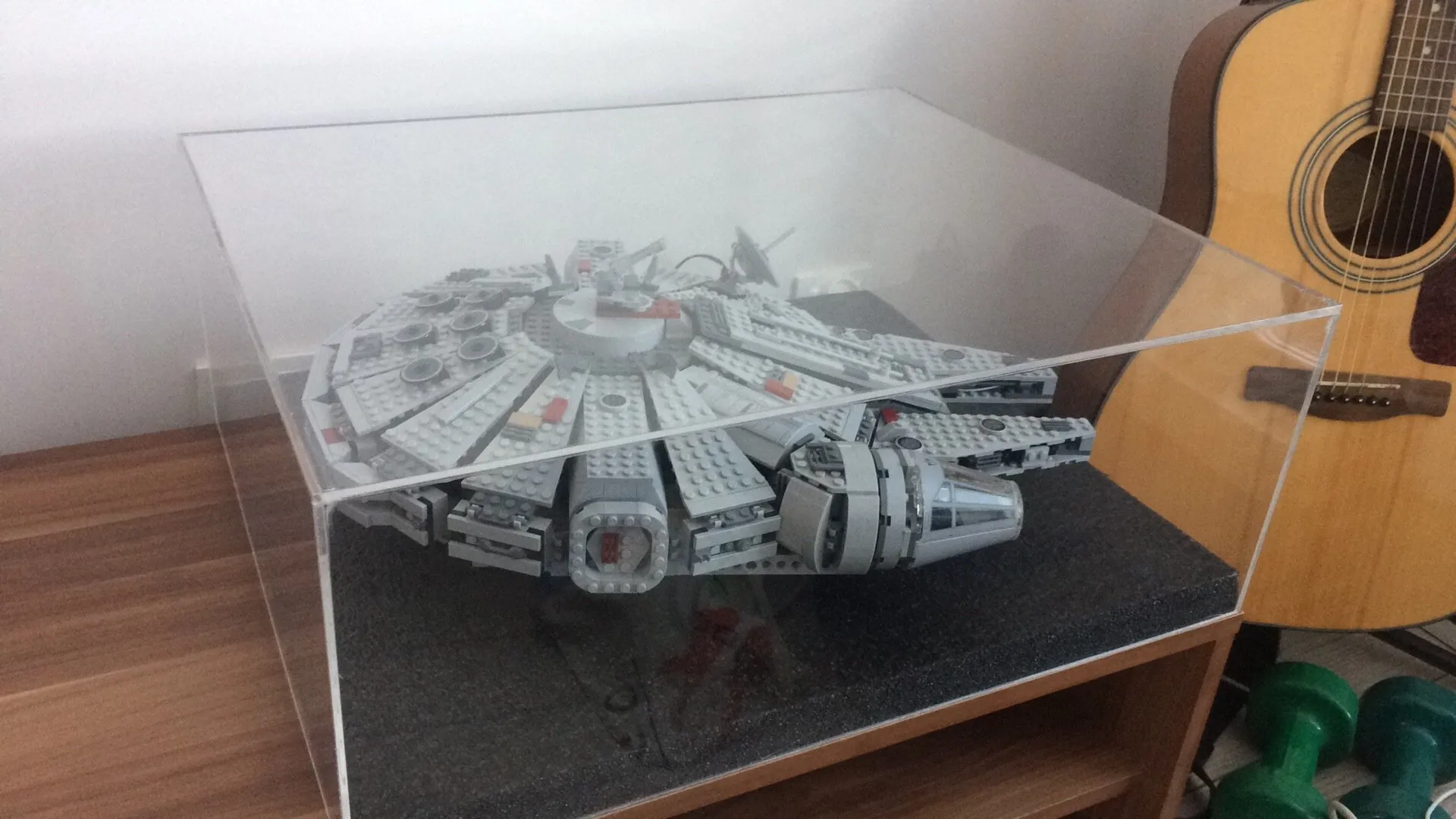The LEGO Millennium Falcon in an acrylic display case, with an acoustic guitar next to it