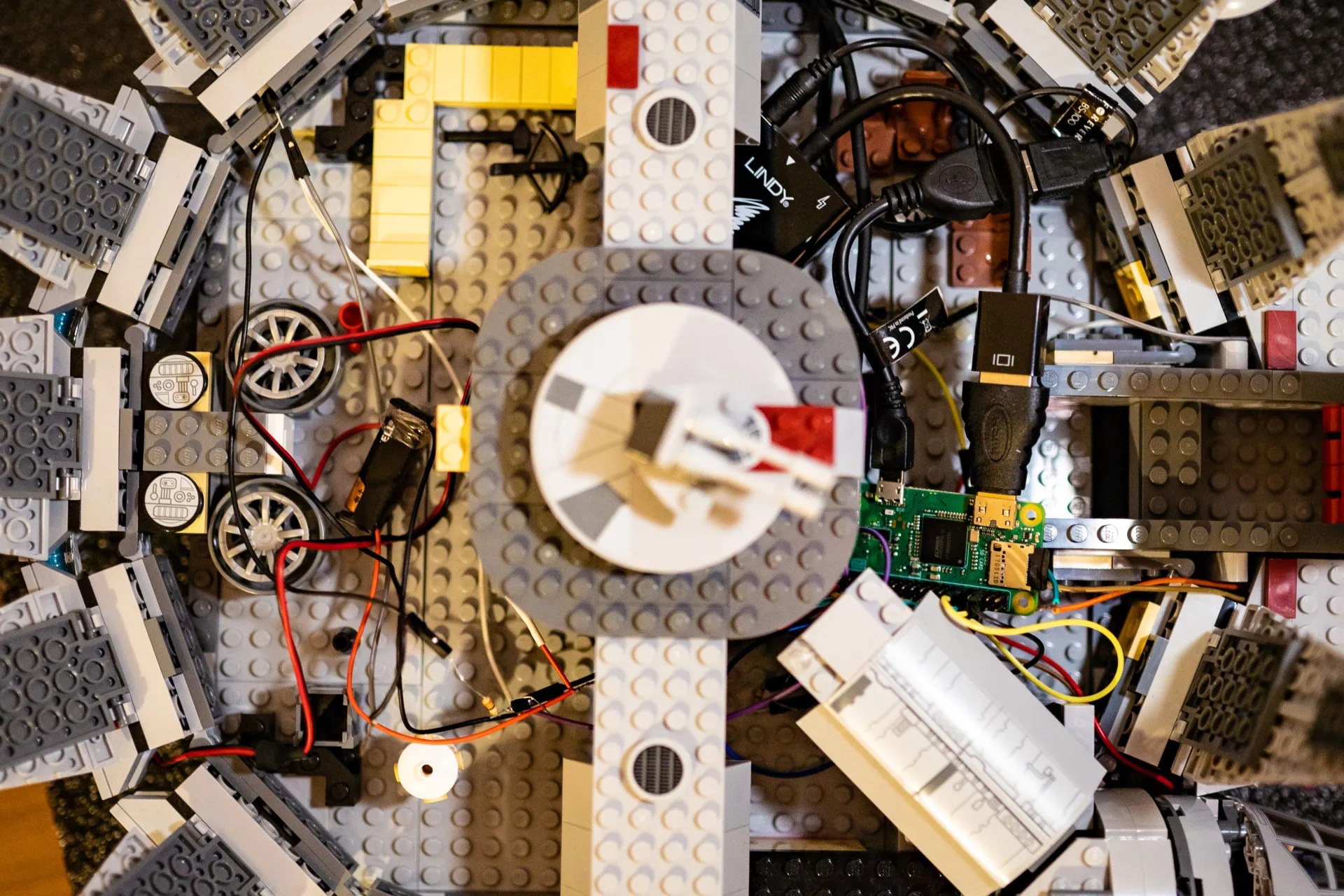 Top-down view of the opened-up LEGO Millennium Falcon: a Raspberry Pi, a tangle of wires, a battery and electronic parts inside