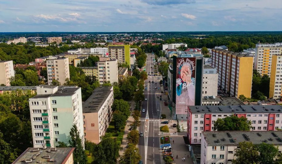 Drone panorama of Białystok: an avenue between apartment blocks, with the Grandma Eugenia mural on a high-rise in the middle of the frame