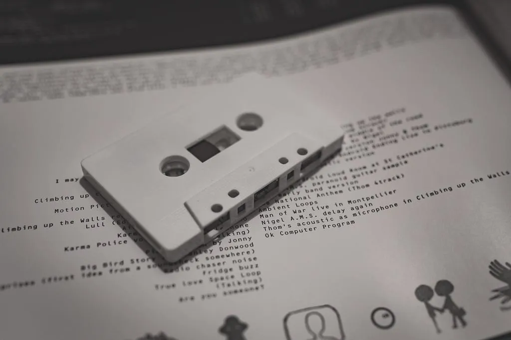 White C90 cassette from the OKNOTOK box lying on a printed track list