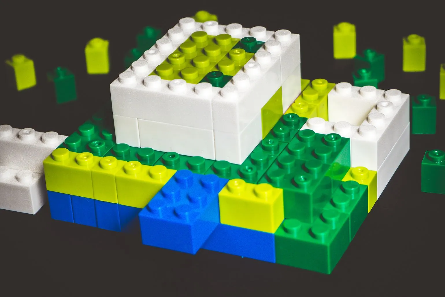 White, green, yellow and blue LEGO block surrounded by single green bricks